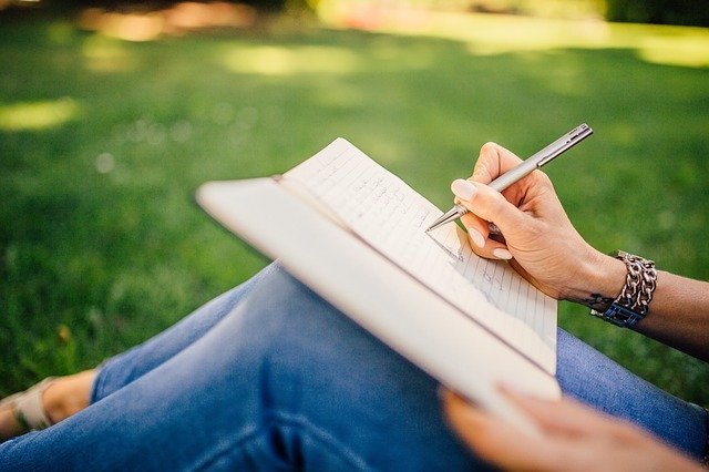 Woman with journal propped on her knees writing in it